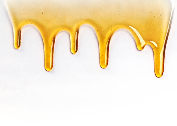 istock Dripping golden sweet honey flowing down the frame from the top over white with copyspace and text 1174335580