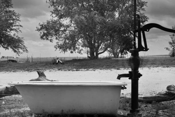 A bathtub outside with a water spout. In black and whtie