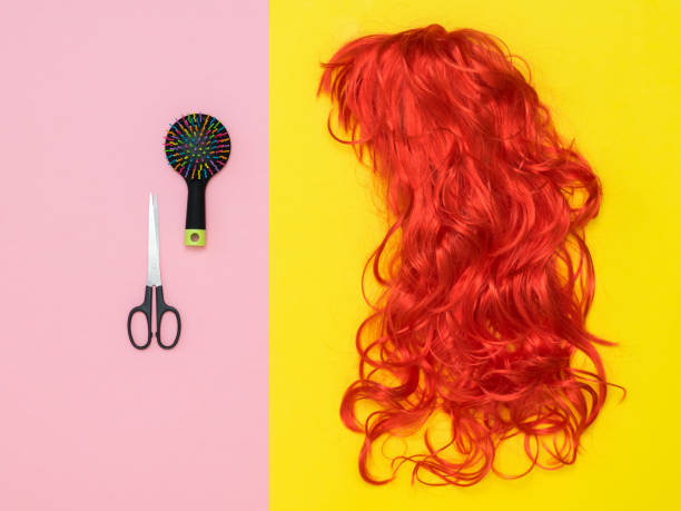istock Scissors, comb and orange wig on yellow and pink background. Accessories to create style. Flat lay. 1174336501