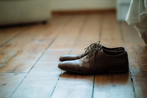 Shot of two formal men’s shoes on the floor of a bedroom