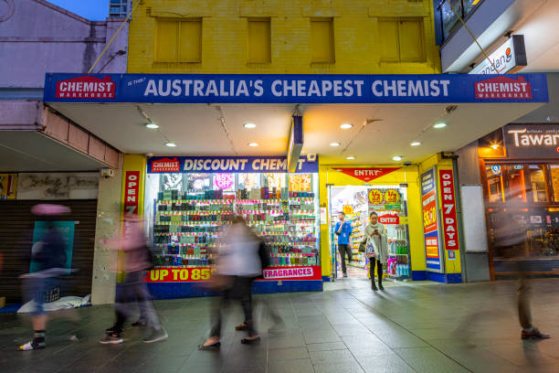 Sydney, Australia - September 12, 2019: Pedestrians walk past an illuminated Chemist Warehouse on Victoria Avenue in Chatswood, Australia on September 12, 2019.   Chemist Warehouse is a privately held Australian company operating a chain of franchised retail pharmacies across Australia and New Zealand.