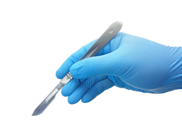 Hand of surgeon in blue medical glove holding a scalpel with blade Hand of surgeon in blue medical glove holding a stainless steel scalpel handle with blade isolated on white background with clipping path scalpel photos stock pictures, royalty-free photos & images