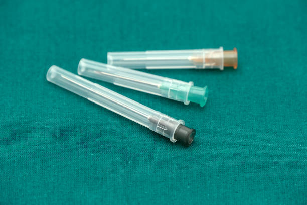 istock Injection needle with cover isolated on surgical green drape 1174345468