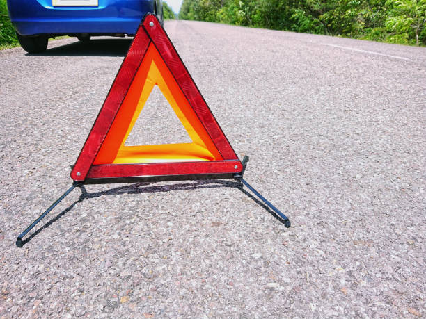 istock Emergency red warning triangle on the road sign with blue broken car 1174346927