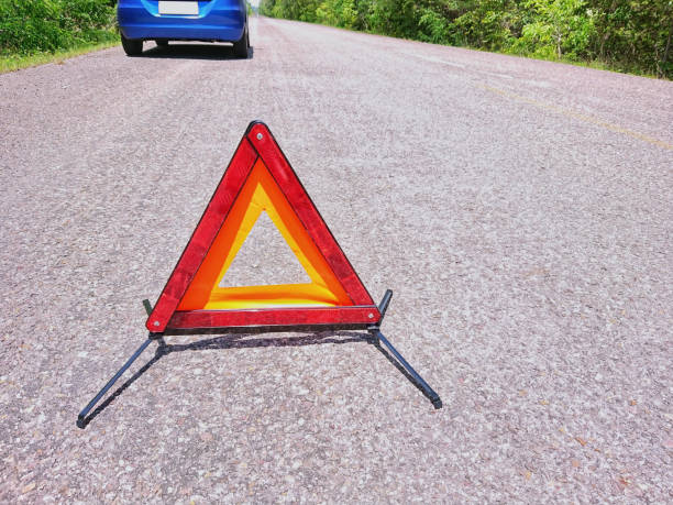 istock Emergency red warning triangle on the road sign with blue broken car 1174346936