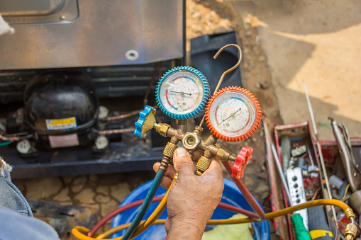 repair refrigerator job with pressure gauge , technician vacuum system refrigerator at maintenance shop.