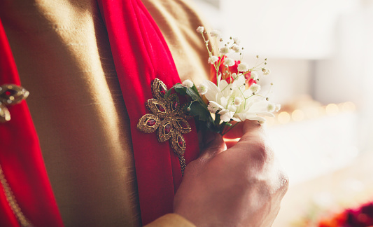 Cropped shot of a man putting a corsage in his pocket in preparation for his wedding day
