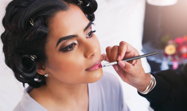 The perfect shade for a special day Shot of a beautiful young woman getting her makeup done on her wedding day makeup artist stock pictures, royalty-free photos & images