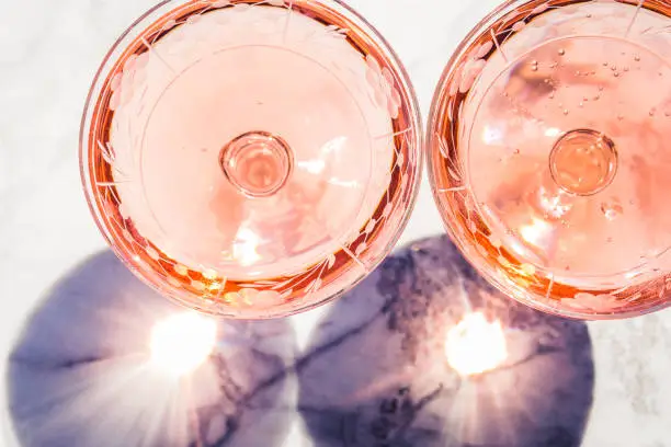 Two crystal stemmed glasses with rose wine on marble table outdoors in a cafe. Aperitif and relax time
