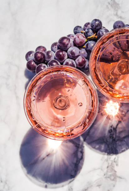 Two crystal stemmed glasses with rose wine Two crystal stemmed glasses with rose wine on marble table outdoors in a cafe. Aperitif and relax time cafe transparent glass table stock pictures, royalty-free photos & images