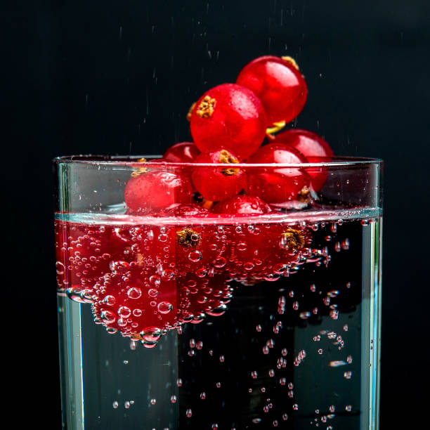 Red currant on mineral water on black background.