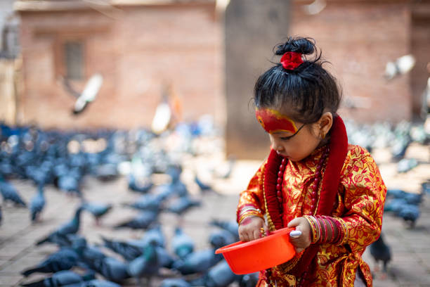 Little girl dressed as Kumari God feeding the pigeons at Kathmandu Durbar Square during Indra Jatra Festival