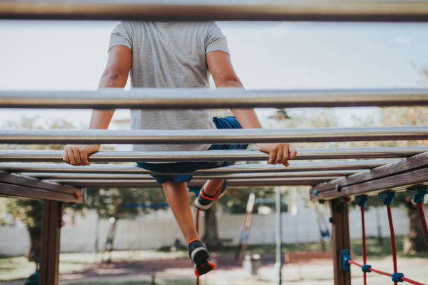istock Low Section Of Man Sitting On Monkey Bars In Playground 1174394439