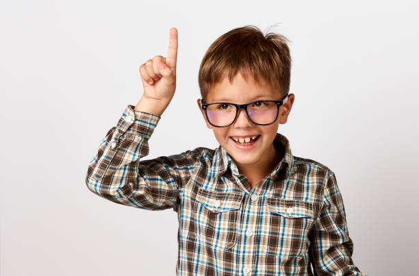 nahaufnahme porträt kind mit brille lesen buch, weißer hintergrund - moving up child pointing looking stock-fotos und bilder