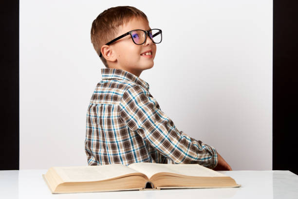 istock School boy sitting turn back at the table with school book 1174398936