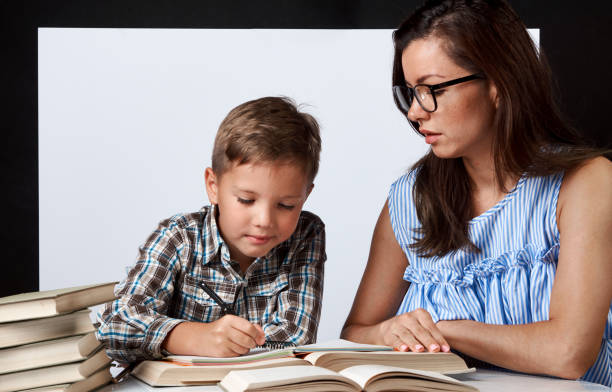 istock Teacher and young boy reading book over white background 1174399122