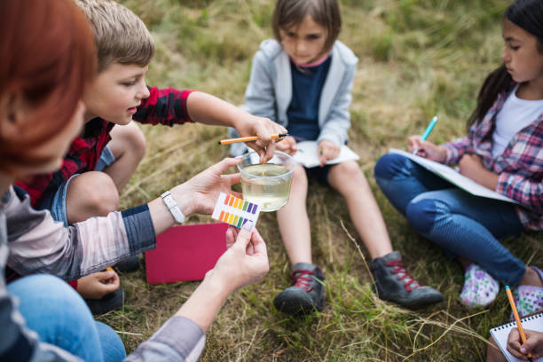 groupe d'enfants d'école avec l'enseignant sur le voyage de champ dans la nature, apprenant la science. - science education school offspring photos et images de collection