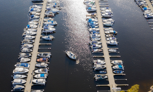 Aerial View by Drone of Yacht Club and Marina. Top view of yacht club. White boats in sea water. Marina dock yachts and small motor boats. Yacht and sailboat is moored at the quay