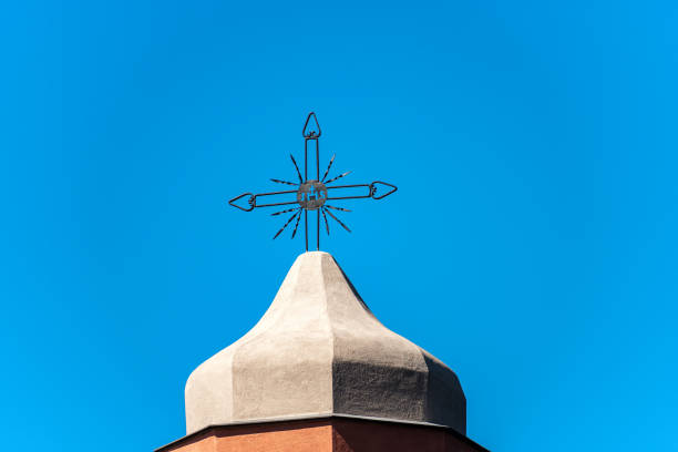 Close-up of a wrought iron cross on a clear blue sky on the top of a bell tower, Christian religious symbol. Church of San Giorgio, Tellaro, La Spezia, Liguria, Italy
