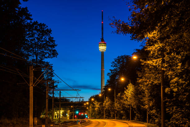 Germany, Empty street alongside railway leading to famous television tower of stuttgart city, called fernsehturm by night in magical twilight atmosphere Germany, Empty street alongside railway leading to famous television tower of stuttgart city, called fernsehturm by night in magical twilight atmosphere stuttgart photos stock pictures, royalty-free photos & images