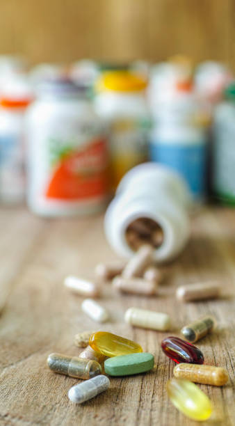 カプセル内の多くの栄養健康補助食品やビタミン, 背景に彼らのボトルと木製の背景に錠剤, 焦点の浅い深さ. - nutritional supplement fish oil vitamin pill bottle ストックフォトと画像