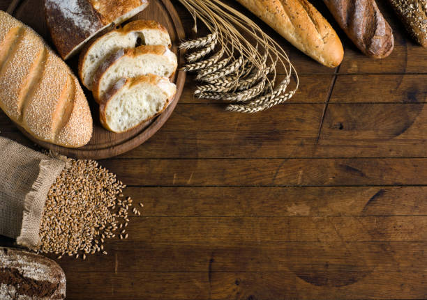 istock Assortment of bread and wheat on wooden table. 1174408565