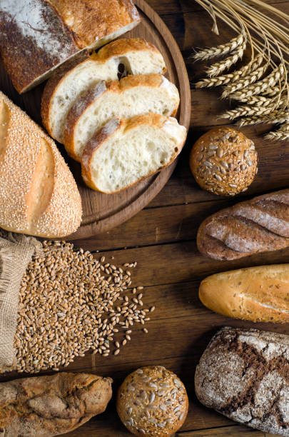 istock Assortment of bread and wheat on wooden table. 1174409599