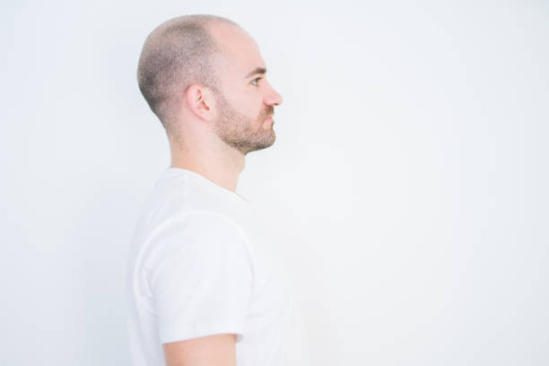 Young bald man over white isolated background looking to side, relax profile pose with natural face with confident smile.