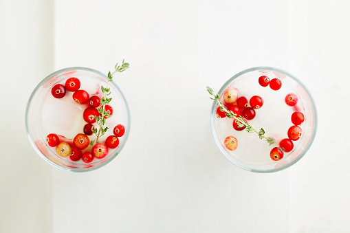 Christmas and thanksgiving vegan cocktail white coconut margarita with cranberries and branch of thyme on white background top view with copy space. Minimalistic concept. Ideas for drinks for celebrate. Horizontal orientation