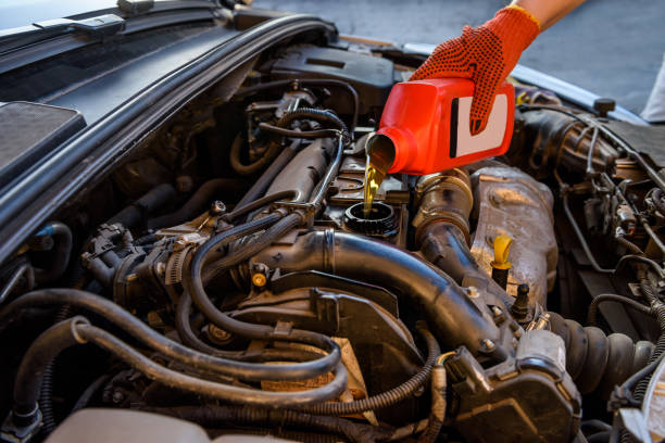 istock Male hands with oil bottle above car engine 1174412151