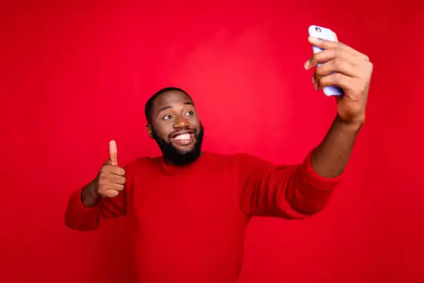 Portrait of his he nice attractive cheerful cheery glad content bearded, guy taking making selfie showing thumbup leisure blog blogger isolated over bright vivid shine red background