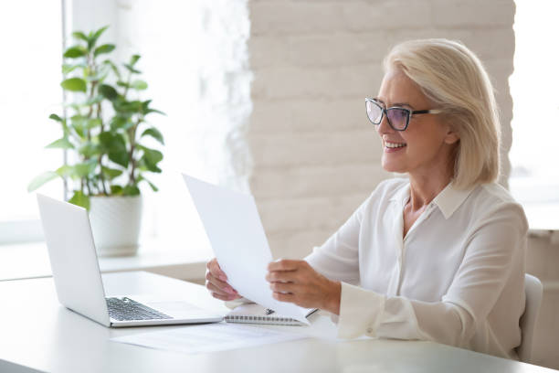 istock Smiling middle-aged businesswoman reading paper document in office 1174414017