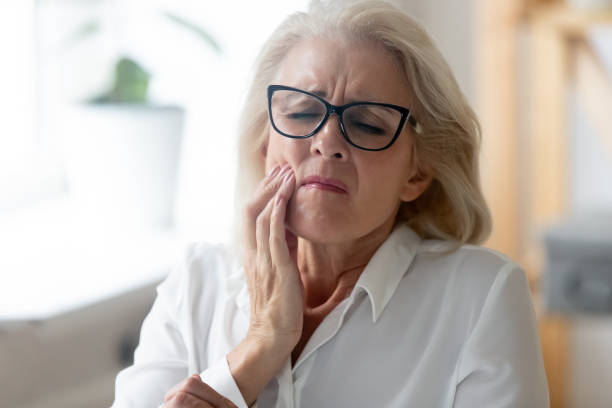 Unhealthy senior woman touch cheek suffering from toothache Hurt senior female worker in glasses feel stressed suffering from severe toothache at workplace, unhappy aged woman employee in glasses feel bad stressed having teeth pain, need dental treatment toothache stock pictures, royalty-free photos & images