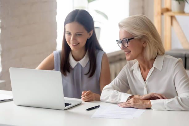 istock Smiling female employees work at laptop in office together 1174414184