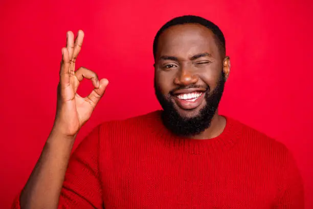 Close-up portrait of his he nice attractive cheerful cheery content positive glad flirty, bearded guy showing ok-sign ad advert solution isolated over bright vivid shine red background