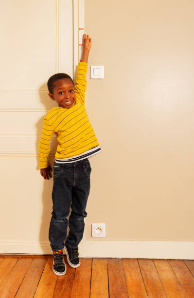 istock boy stretch his hand to measure height on door 1174416710