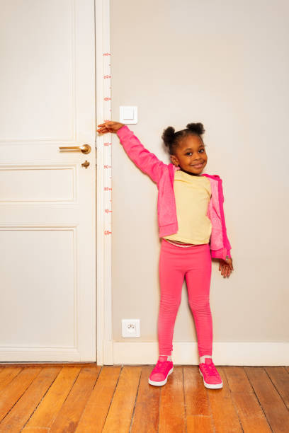 istock Little girl over scale on wall measure height 1174416720