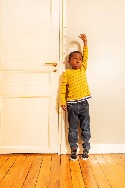 istock boy measuring his height benchmark on door at home 1174416731