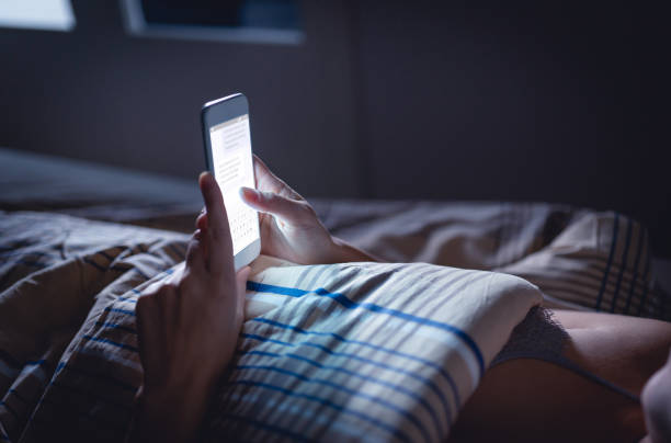 femme utilisant le téléphone tard la nuit dans le lit. personne regardant des messages texte avec la cellule dans la maison foncée. hipster rencontres en ligne ou sms avec smartphone. sexting ou concept de tricherie. - bedtime photos et images de collection