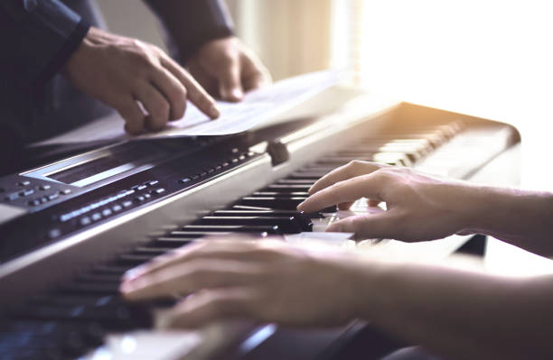 Piano teacher and student practising. Music lesson and course in school. Man learn playing with tutor in class. Mentor teaching pianist. Band practise. Two guys training.
