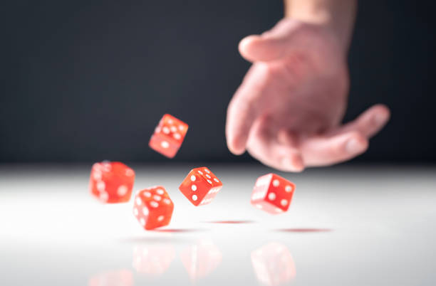 Hand throwing and rolling dice. Gambler tossing five red poker and casino dice on table. Man gambling or playing board game. Hand throwing and rolling dice. Gambler tossing five red poker and casino dice on table. Man gambling or playing board game. Risk, luck, betting or addiction concept. dice photos stock pictures, royalty-free photos & images