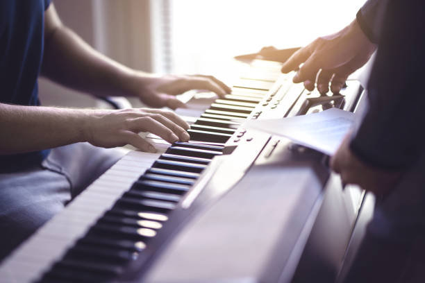 istock Music lesson and course. Piano teacher and student practising in school. Man learn playing with tutor in class. Two guys training. Mentor teaching pianist. Band practise. 1174418482