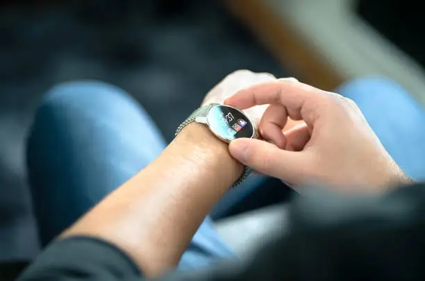 Smart watch, wearable gadget. Man wearing hybrid smartwatch. Wearables with digital touchscreen and mobile app technology. Person using wristwatch for business and work. Device with touch interface.