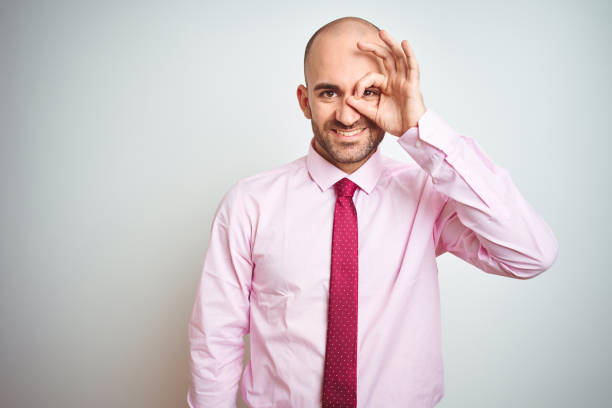 istock Young business man wearing pink tie over isolated background doing ok gesture with hand smiling, eye looking through fingers with happy face. 1174420161