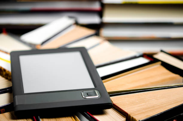 istock The e-book with a white screen lies on the open multi-colored books that lie on a dark background, close-up 1174421186