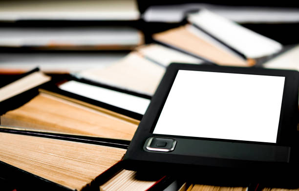 istock The e-book with a white screen lies on the open multi-colored books that lie on a dark background, close-up 1174421191