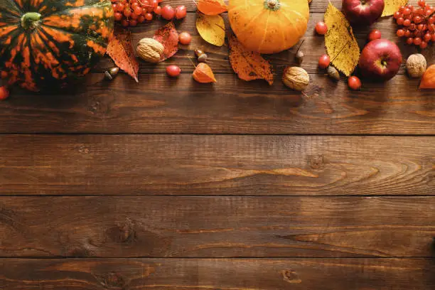Happy Thanksgiving concept. Autumn composition with ripe orange pumpkins, fallen leaves, dry flowers on rustic wooden table. Flat lay, top view, copy space.