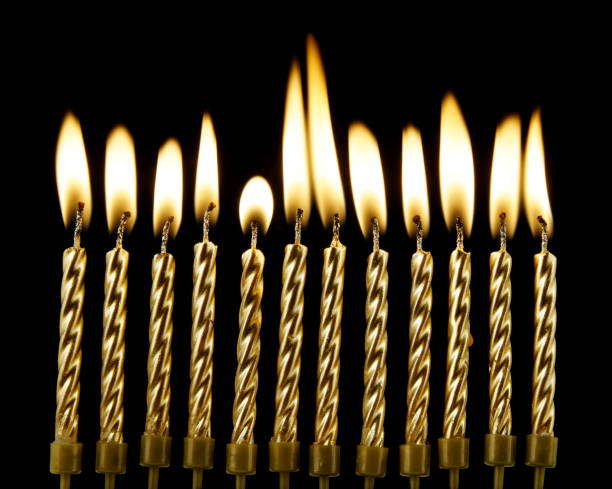 istock Burning golden candles on black background 1174423020
