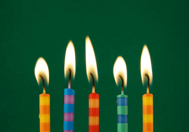 istock Burning colorful candles on green background 1174424238