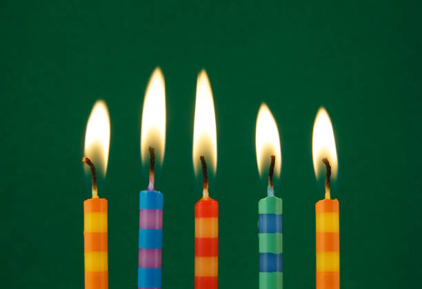 istock Burning colorful candles on green background 1174424243